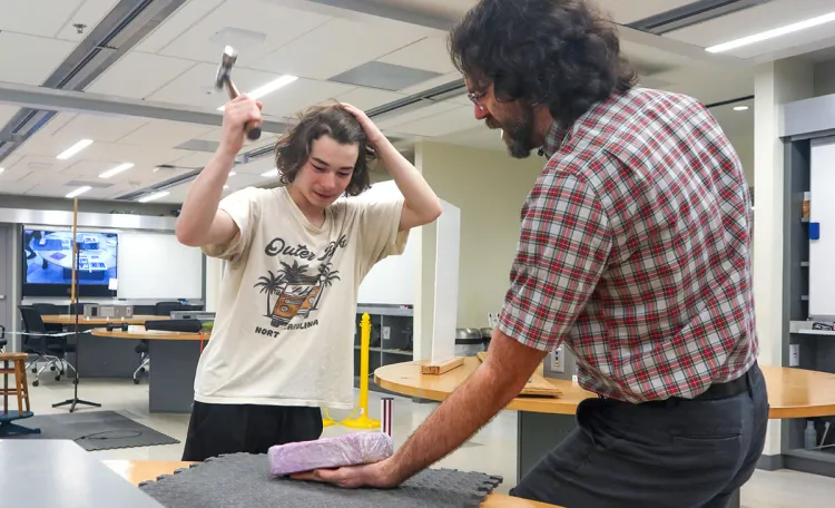 Physics lecturer Luke Donforth places his faith in science as a visiting student participates in a materials demonstration.