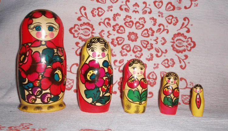 A set of five matryoshka, or wooden nesting dolls standing in a line. The dolls decrease in size very uniformly.