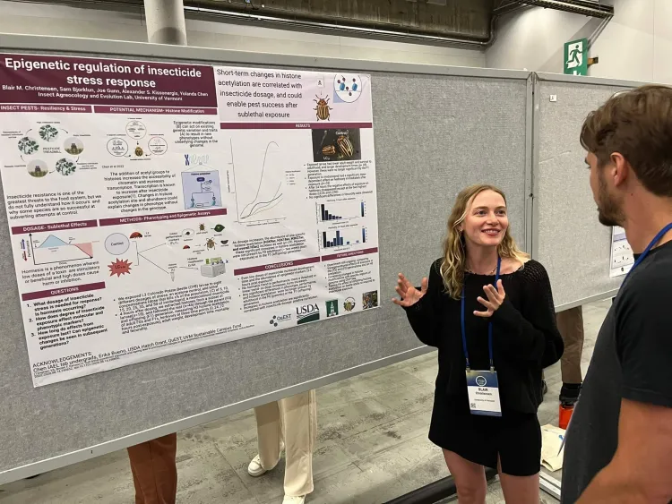 A woman presenting scientific findings in front of a posterboard