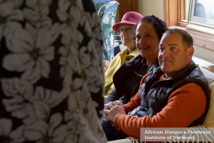 Three people sit in a row on a couch, smiling.