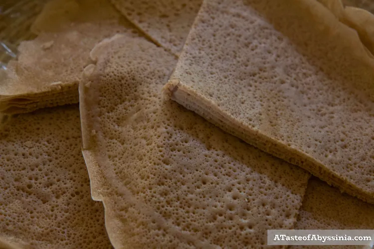 Spongy-looking, tan flat bread cut from a circle into quarters. There are several pieces on top of one another.