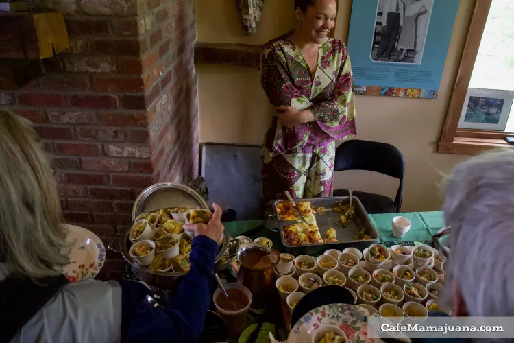 A woman smiles while people put food samples on their plates.