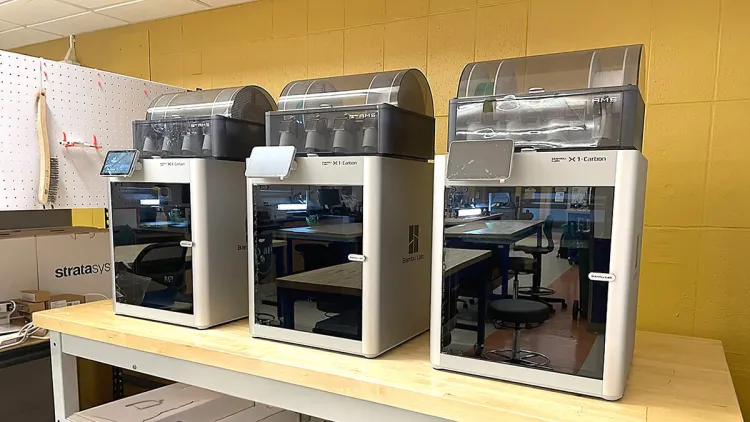 Three identical 3D Printers lined up on a production table