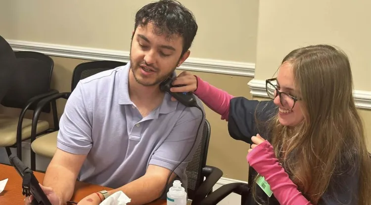 2 people sitting at a table using an ultrasound device