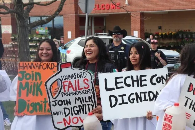 People standing holding signs in front of a grocery store