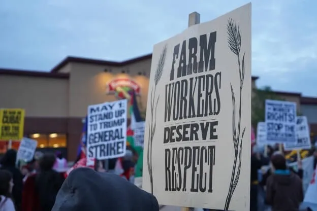People hold signs in front of a grocery store