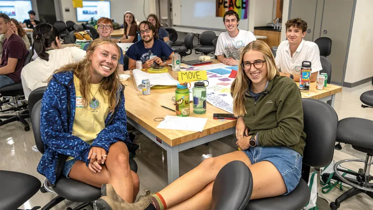 A group photo of students gathered around a table during a meeting