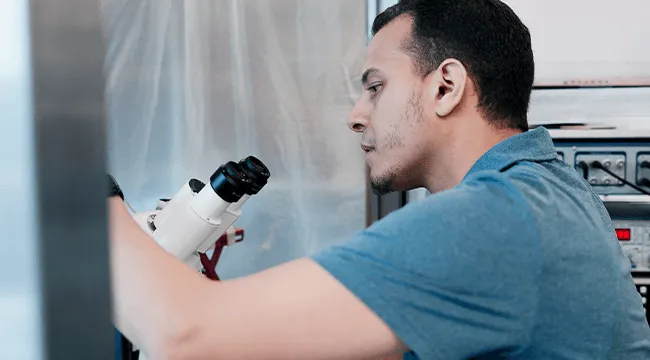 Person adjusting a microscope in a laboratory setting. 