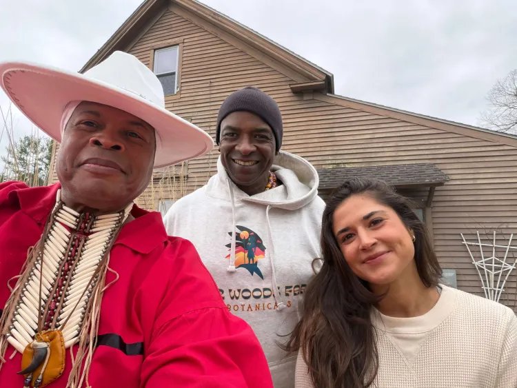 A woman and two men in front of a barn