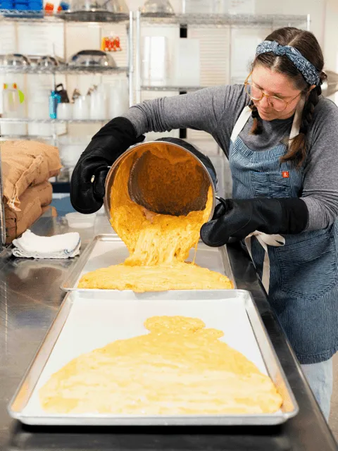 A woman pours batter into a pan