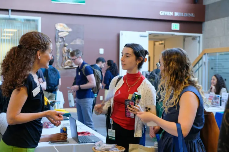 woman talking to two new students at a tabling resource event