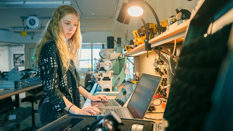 A researcher working at a lab table with an open laptop