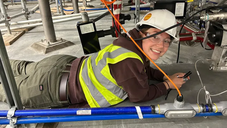 A student intern inpects the installation of new equipment while wearing protective gear