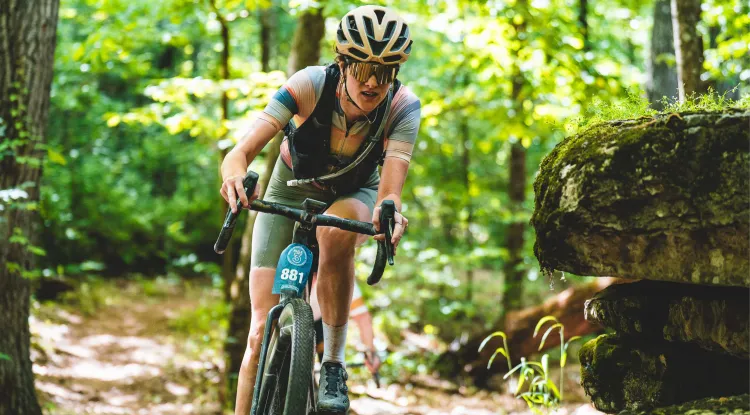a person riding in a bike race through woods