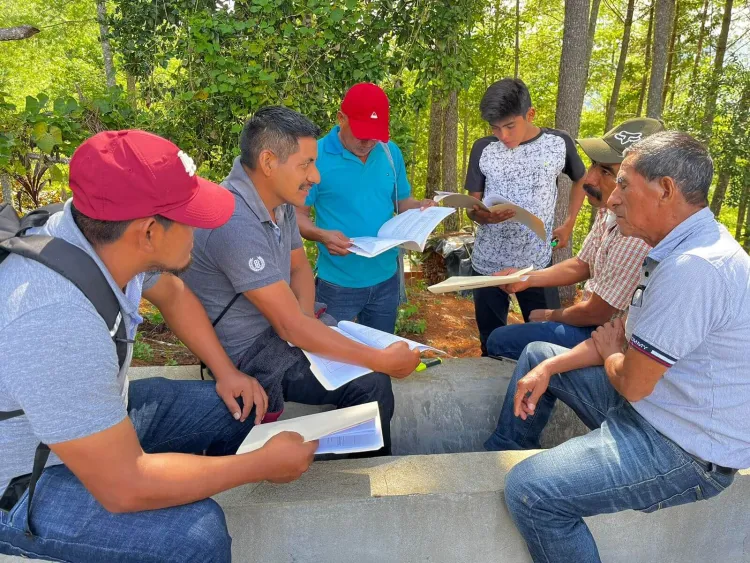 Six men in jeans and t-shirts look at papers together. 