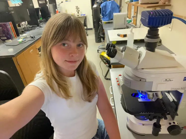 young woman works in lab with microscope
