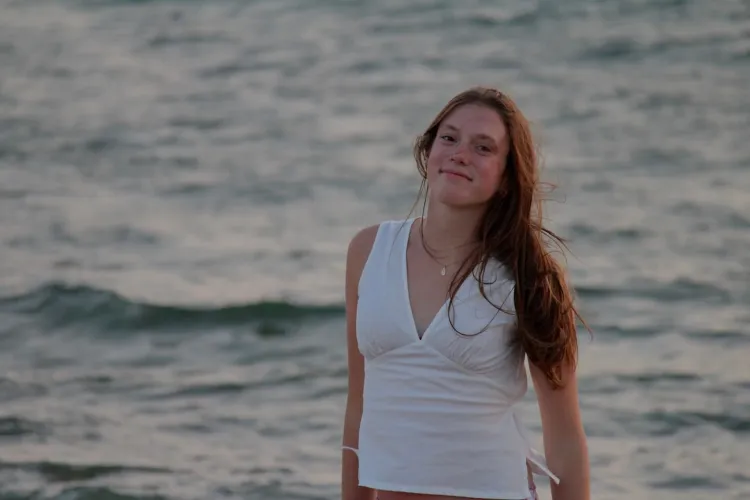 young woman stands near water