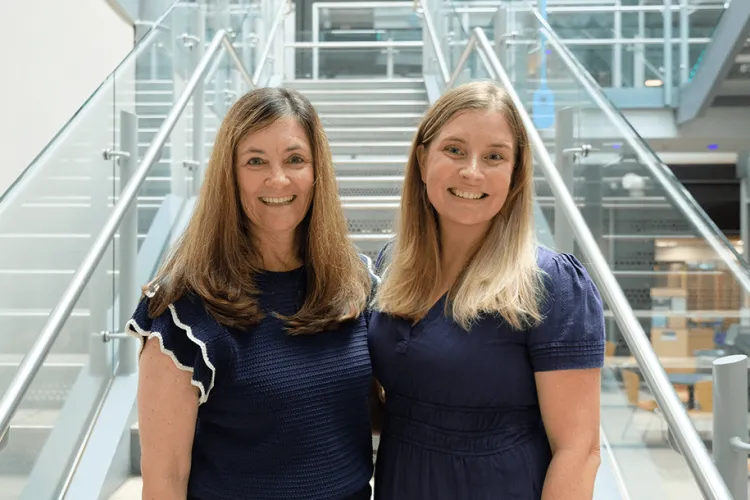 Two people on the staircase smiling in navy blue attire. 