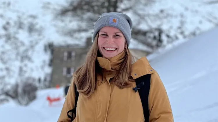 Person smiling outdoors in a snowy setting.