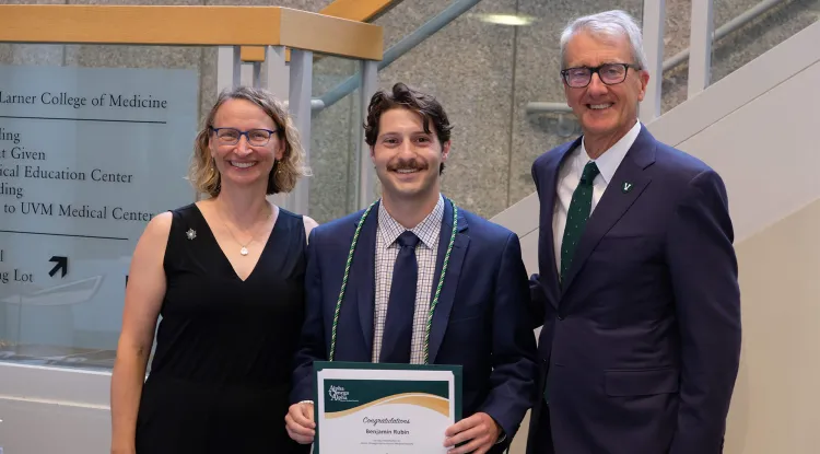 2 people flanking a person holding an award certificate