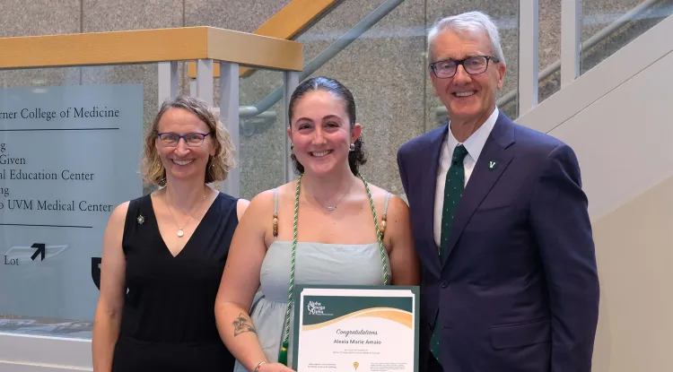 2 people flanking a person holding an award certificate