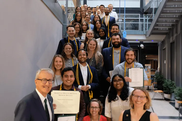 A large group of people in formal attire on a staircase with some individuals holding certificates up. 
