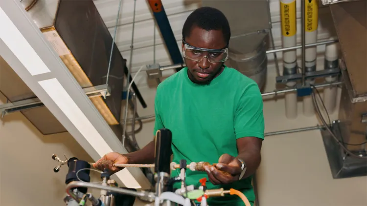 grad student in goggles conducts experiment using large chemistry equipment