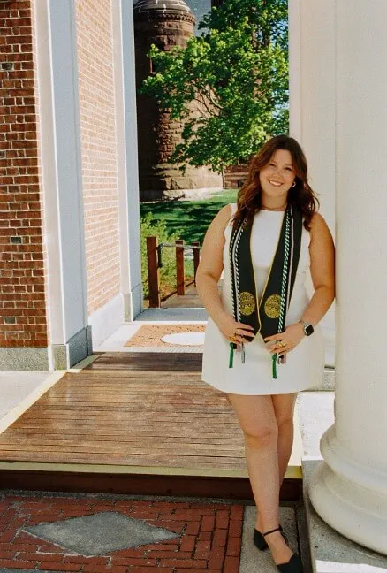 Liv Evans '26 stands by columns on the UVM campus with graduation honors