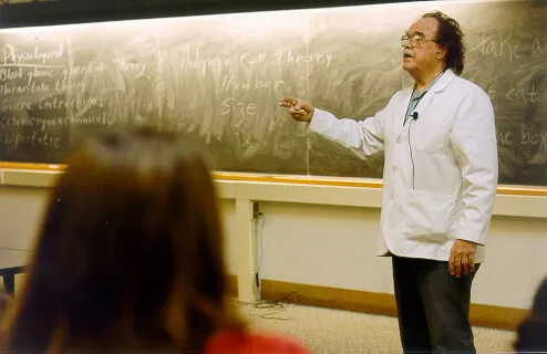 A man in a white coat at a chalkboard