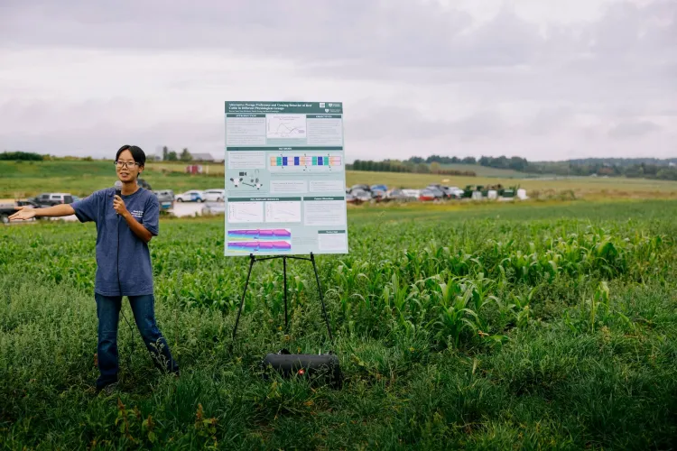 Rowan Yuan gives a poster presentation in a pasture