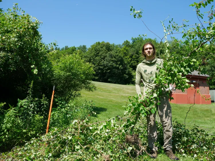 Simon Rae holds up giant vine with winston prouty field behind him
