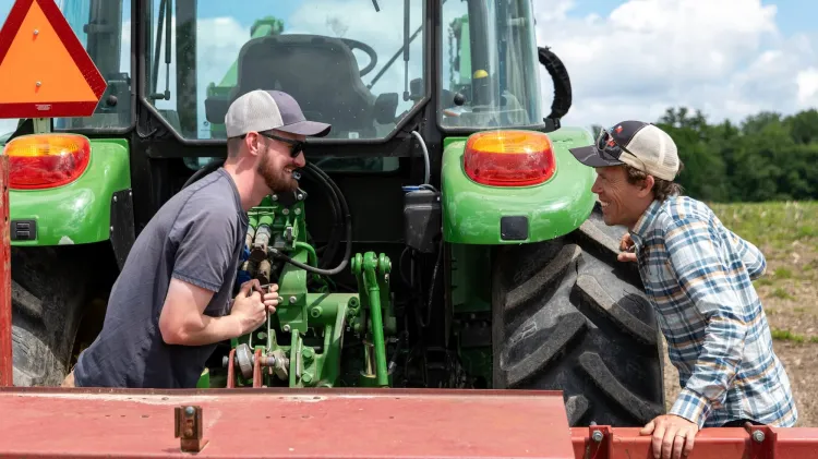 Two men talking and smiling near tractor