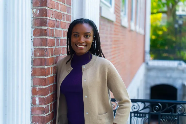 An image of Victoria Lee smiling and leaning against a brick building