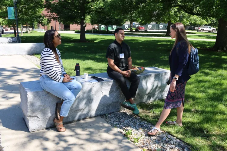 three people gather outside, talking