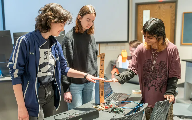 Three students demonstrating a computer science project