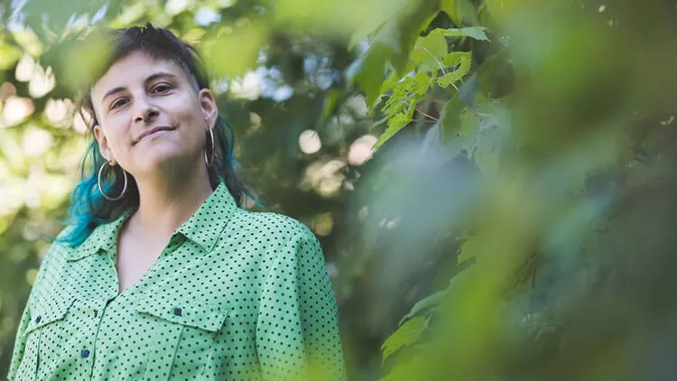 Portrait of E. Ornelas outdoors, wearing a green polka-dot shirt with trees in the background.