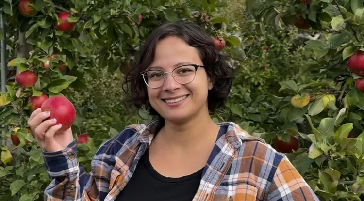 a person holding an apple in an apple orchard