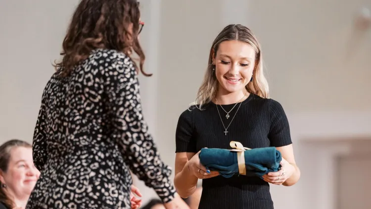 A nursing student receives a green vest at the investiture ceremony