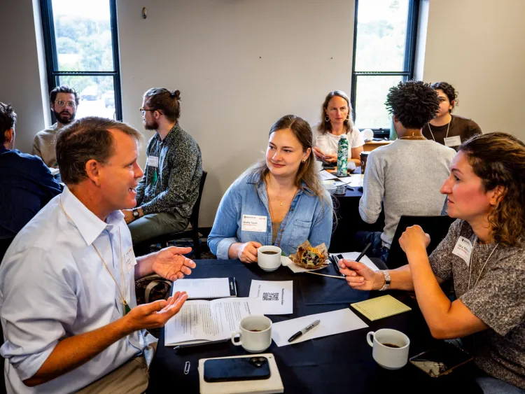 Participants at the 2026 See Change conference discuss ideas around a table.