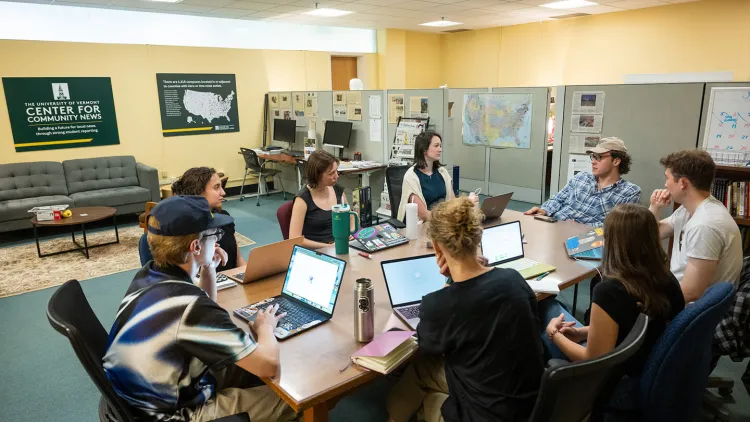 Courtney Lamdin sits at a conference table with seven student journalists during an editorial meeting.