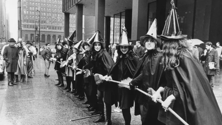 women dressed as witches attend a protest on Wall Street