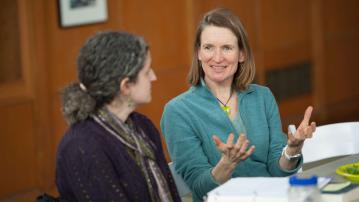 Susan Munkres speaks with a faculty member inside of a university building.