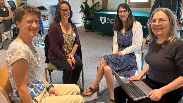 four smiling people sitting in chairs