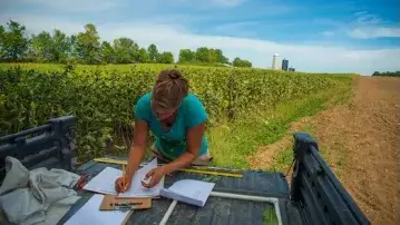 A woman writes in a notebook in the bed of a pickup truck 