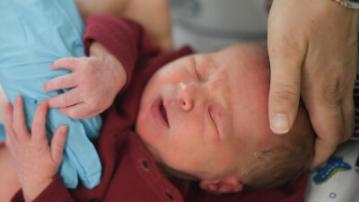 infant surrounded by loving hands