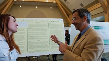 Two people having a conversation at a research fair 