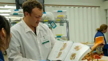 person in white lab coat showing medical images to a student