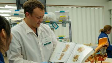 person in white lab coat showing medical images to a student