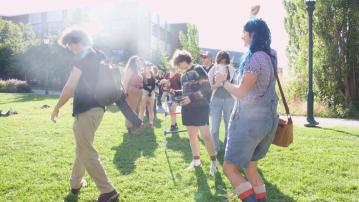 A group of students are on one of the campus greens on a sunny day smiling and socializing at a RSENR event