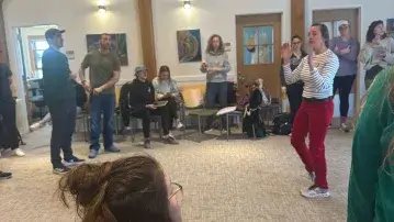 people in an active workshop standing and listening to a speaker